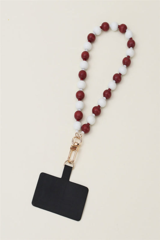 A maroon and white wood beaded phone wristlet with a gold-tone clip and white beads.