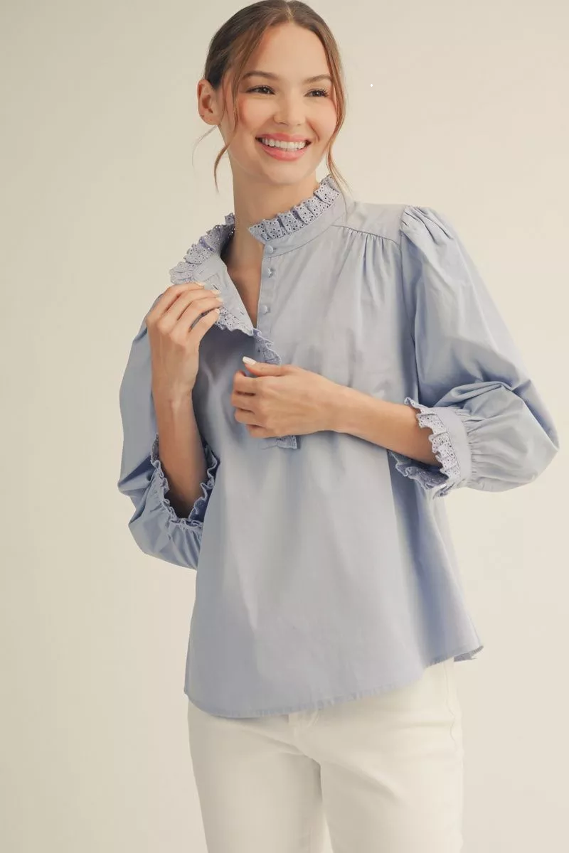 Woman wearing a light blue blouse with ruffled details on a beige background