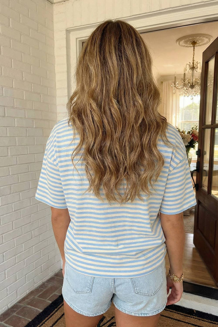 Person wearing a striped shirt and denim shorts standing in a room with a chandelier.
