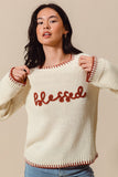 Woman wearing a cream sweater with 'blessed' in red text on a beige background
