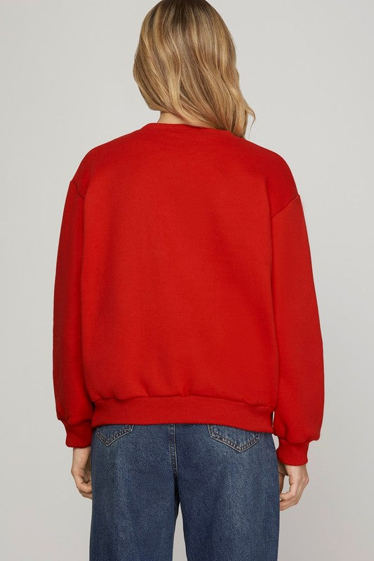 Person wearing a red sweatshirt and blue jeans on a plain background