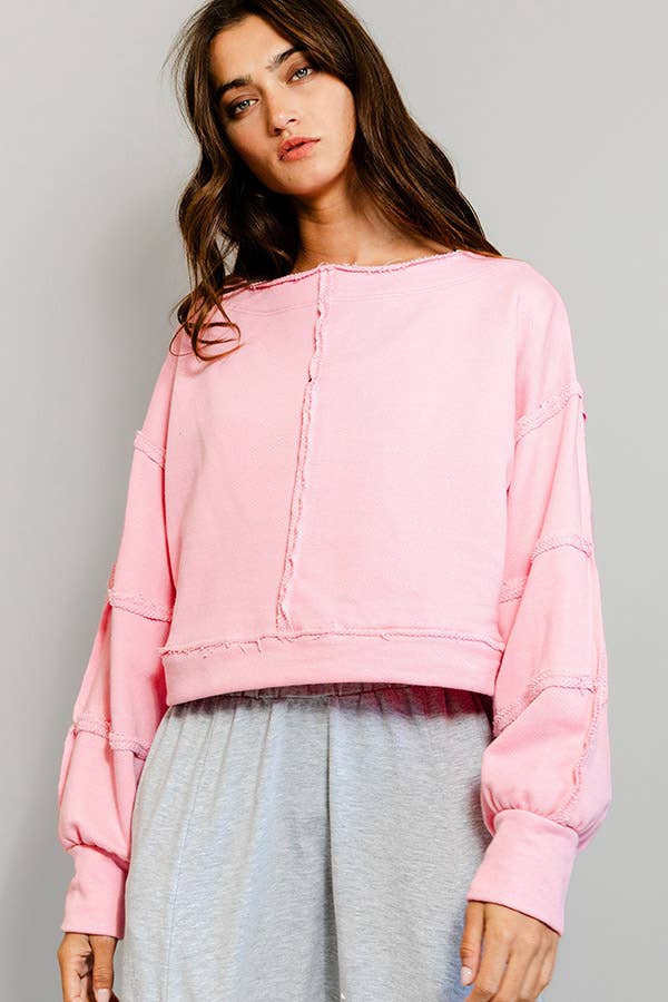 Woman wearing a pink sweatshirt against a gray background
