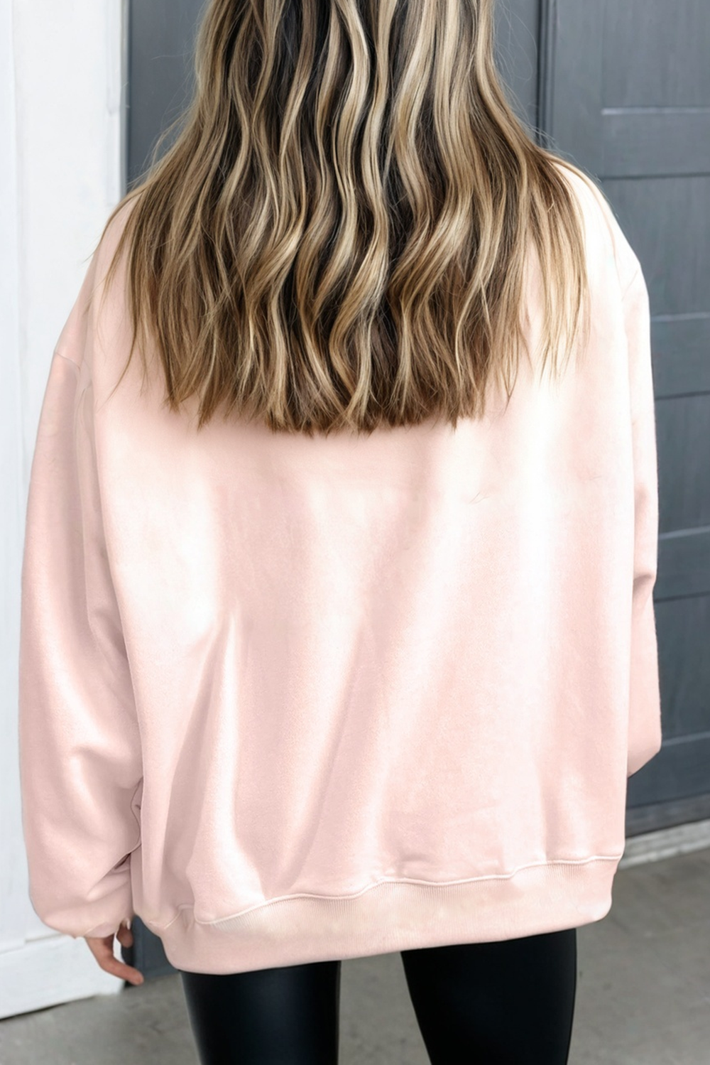 Person wearing a light pink sweatshirt with a neutral background