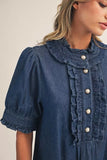 Blue denim dress with ruffled collar and buttons on a neutral background