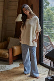 Woman in a cozy living room wearing a beige sweater and blue striped pants.