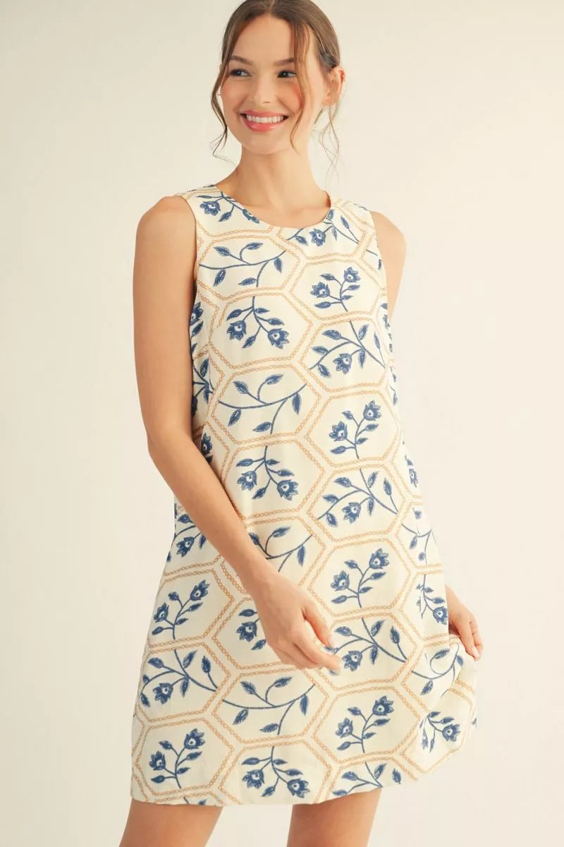 Woman wearing a sleeveless dress with blue floral pattern on a beige background