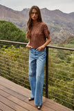 Woman standing on a wooden deck with mountains in the background