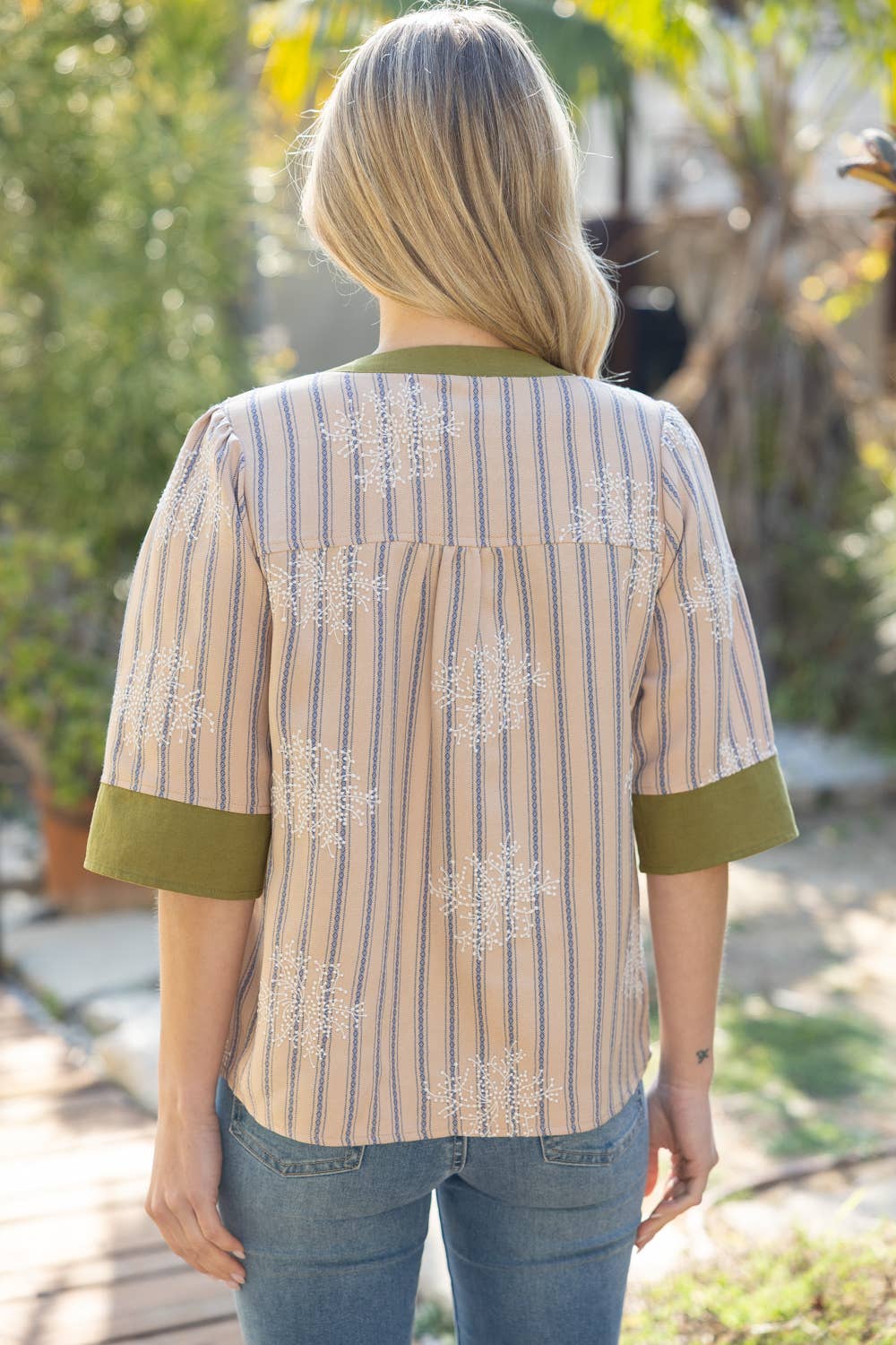 Person wearing a striped shirt with green accents outdoors