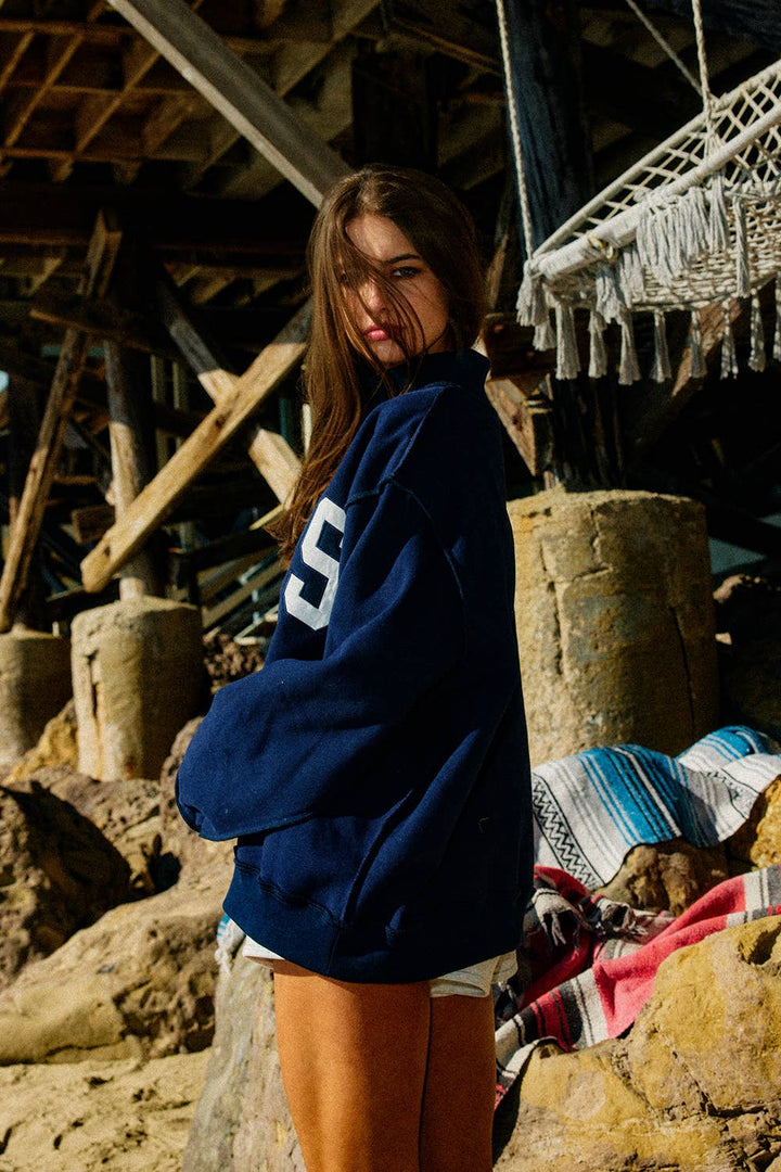 Woman wearing a blue sweatshirt with a white &