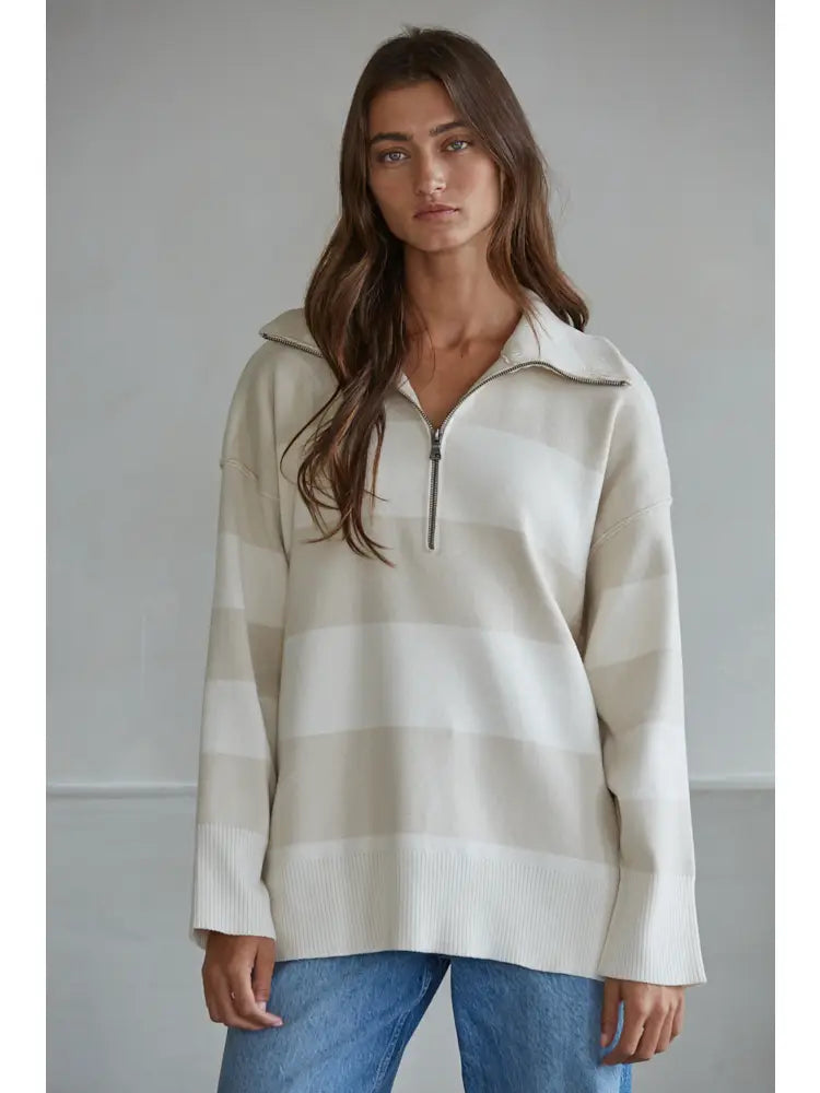Woman wearing a striped sweater and jeans against a plain background