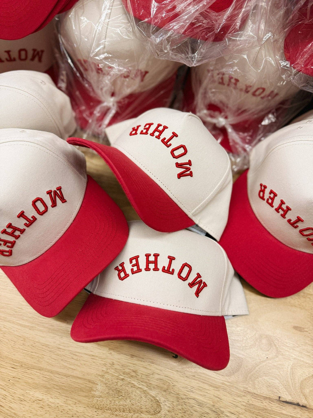 White and red caps with 'MOTHER' text on a wooden surface