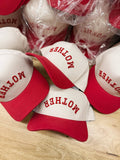 White and red caps with 'MOTHER' text on a wooden surface