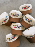 Collection of baseball caps with 'how lucky are we' text on a concrete surface