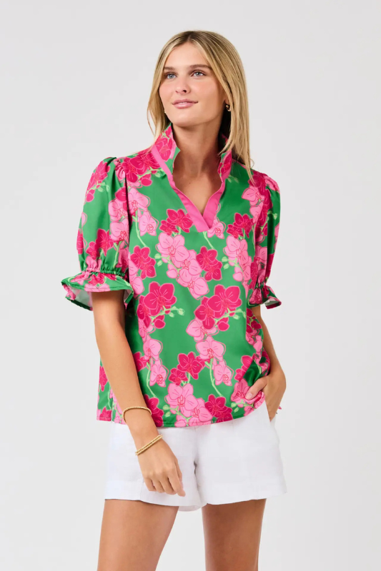 Woman wearing a colorful floral blouse and white shorts on a white background