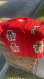Red shirt with gingerbread man designs on a brick surface