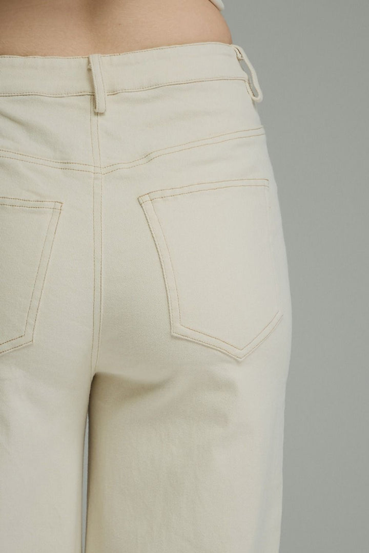 Close-up of the back waistband and back pockets of off-white denim jeans, showing belt loops, stitching, and pocket details against a neutral gray background.