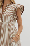 Woman wearing a brown and white striped dress with ruffled sleeves on a plain background