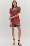 Woman wearing a red plaid dress with green accents on a white background