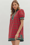 Woman wearing a red plaid dress with green accents on a white background