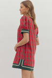 Woman wearing a red plaid dress with white trim on a light gray background