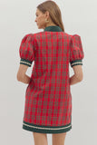 Red plaid dress with green trim worn by a person on a white background