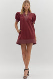 Woman wearing a burgundy dress with puff sleeves on a white background