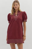 Woman wearing a burgundy dress with puff sleeves on a plain background