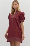 Woman wearing a burgundy dress with puff sleeves on a light gray background