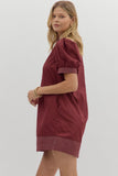Woman wearing a burgundy dress with short sleeves on a white background