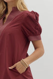 Maroon dress with puff sleeves worn by a person on a plain background