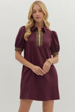 Woman wearing a burgundy dress with gold accents on a white background
