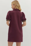 Woman wearing a burgundy dress with leopard print cuffs on a white background
