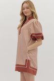 Woman wearing a red and white striped dress with embroidered details on a plain background
