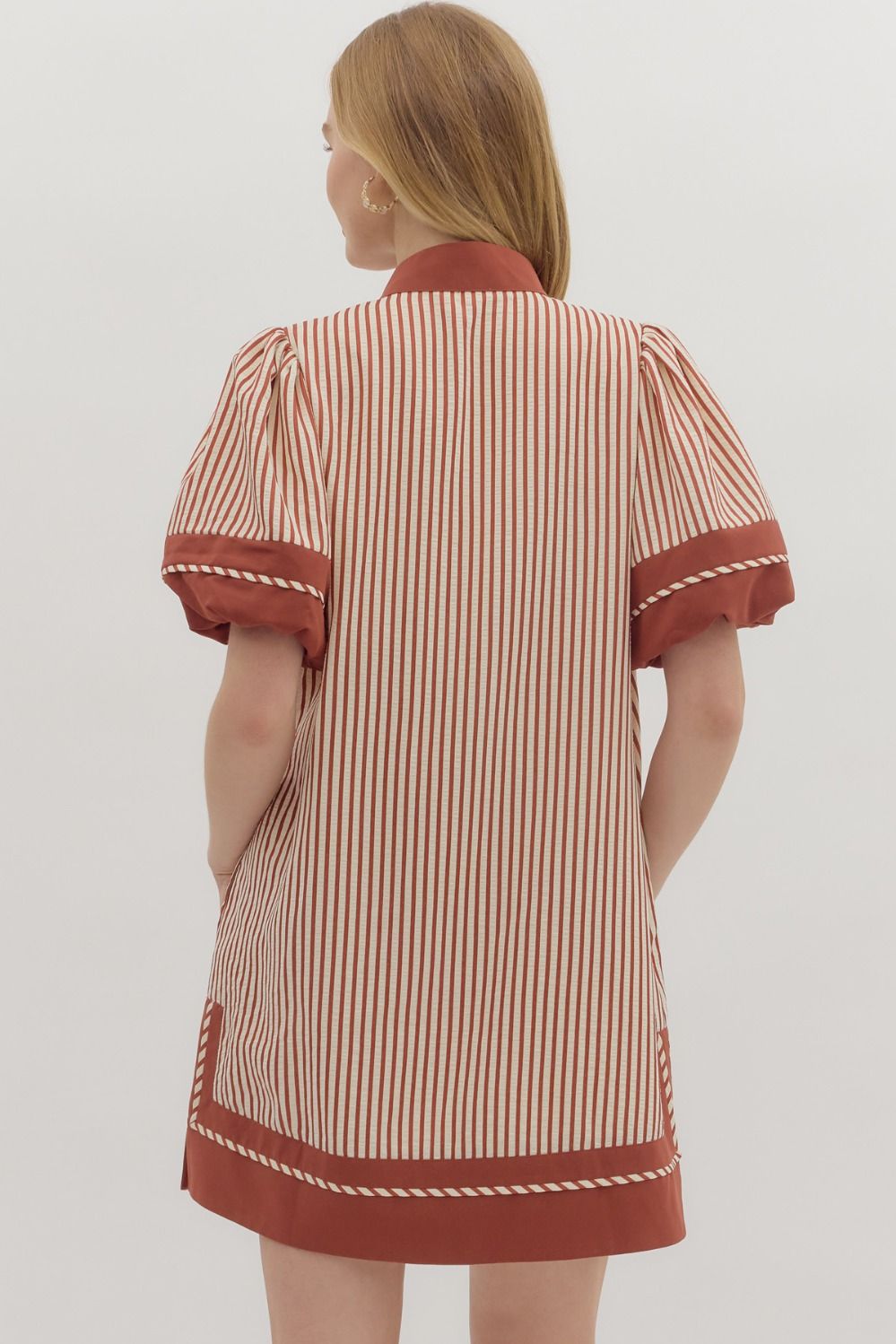 Woman wearing a striped dress with red accents on a plain background