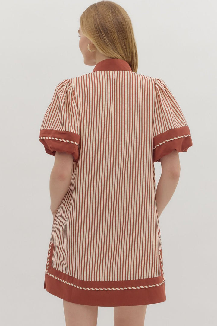 Woman wearing a striped dress with red accents on a plain background