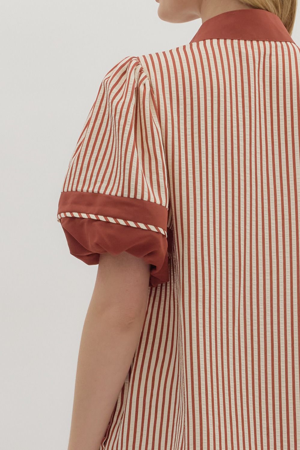 Person wearing a red and white striped dress with a plain background