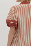 Person wearing a red and white striped dress with a plain background