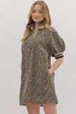 Woman wearing a leopard print dress with puff sleeves on a plain background