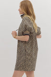 Woman wearing a leopard print dress with black trim on a plain background
