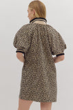 Person wearing a leopard print dress with puff sleeves on a plain background