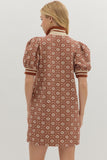 Woman wearing a patterned dress with puff sleeves on a plain background