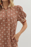 Woman wearing a patterned dress with puff sleeves on a plain background