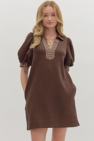 Woman wearing a brown dress with plaid accents on a white background