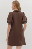 Brown dress with plaid cuffs worn by a person on a white background