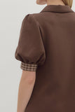 Brown shirt with checkered cuffs on a plain background