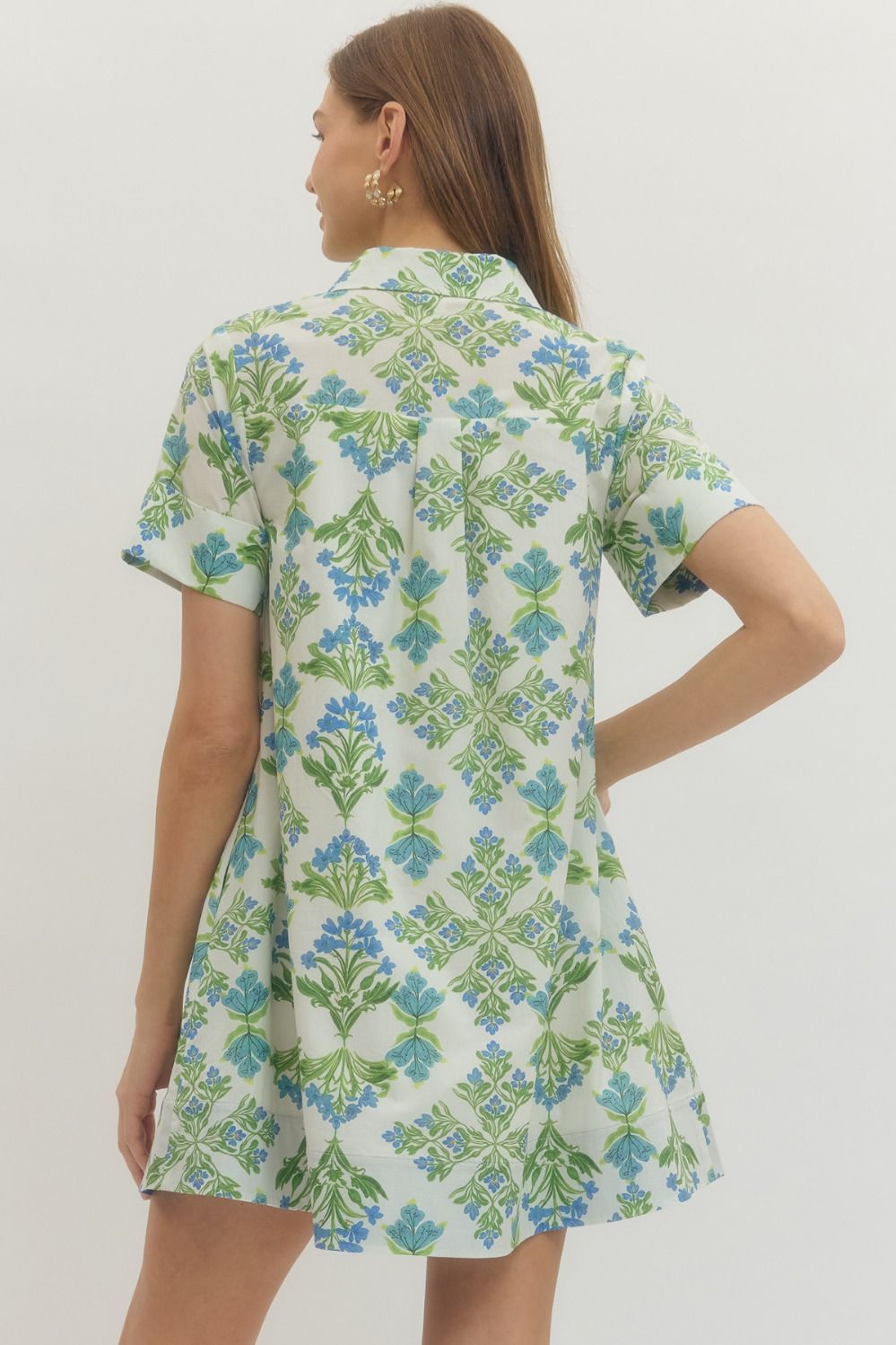 Woman wearing a floral dress with green and blue patterns on a white background