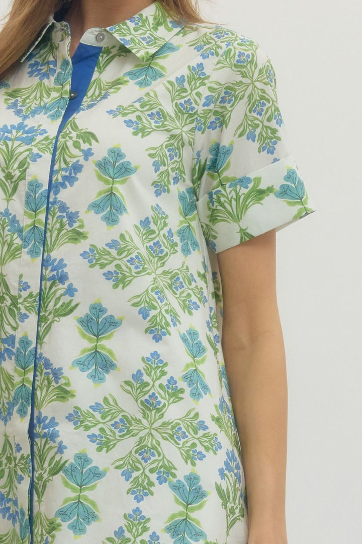 Woman wearing a floral patterned shirt with green and blue flowers on a white background