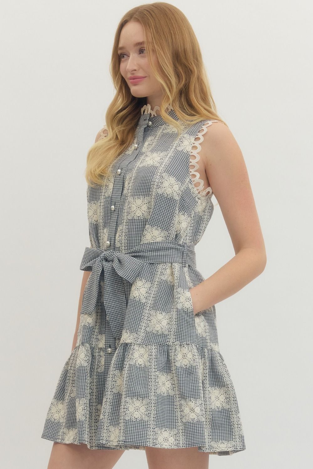 Woman wearing a blue and white checkered dress with a belt on a plain background