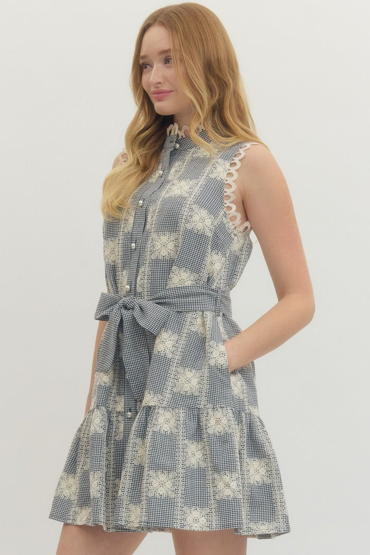 Woman wearing a blue and white checkered dress with a belt on a plain background