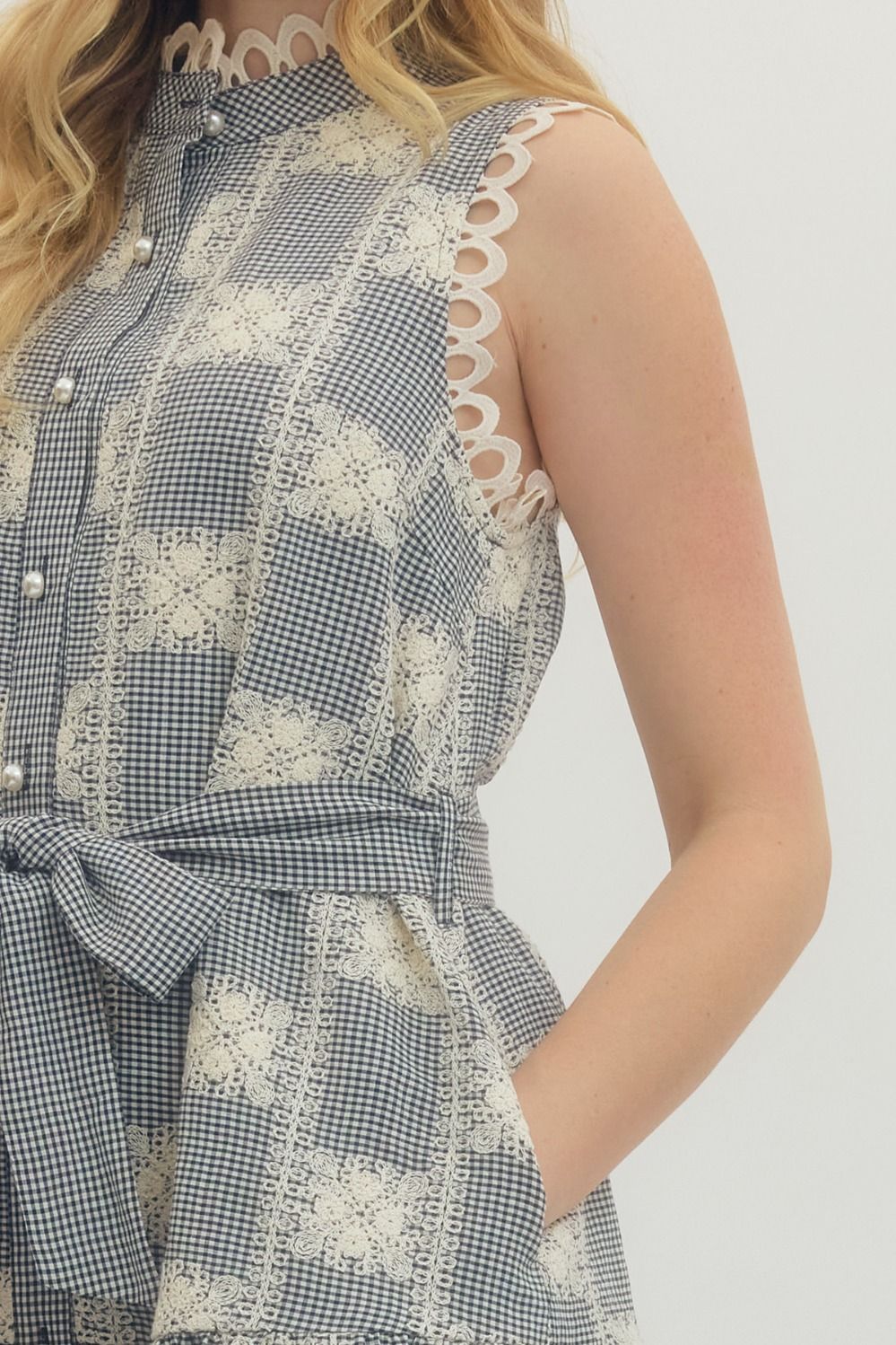 Woman wearing a blue and white checkered dress with lace details on a plain background